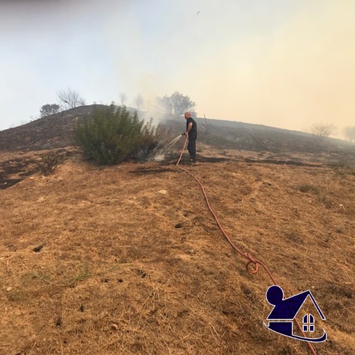 A person standing on top of a hill near smoke.
